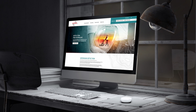 Ordinateur affichant le site web de Géoradar Détection sur un bureau avec lampe et fenêtre en arrière-plan.