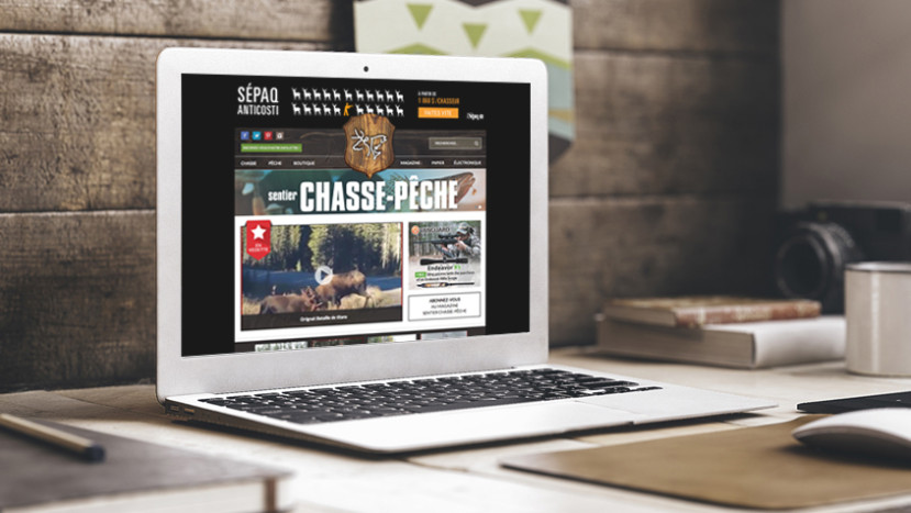 Ordinateur portable affichant le site web de Sentier Chasse-Pêche sur un bureau en bois avec livres et tasse.