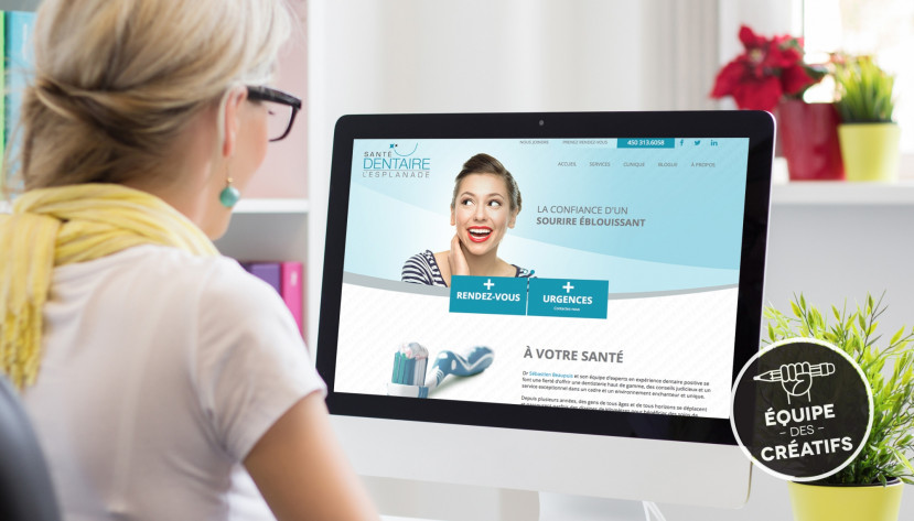 Femme regardant le site web de Santé Dentaire l’Esplanade sur un écran d'ordinateur dans un bureau lumineux avec plantes.