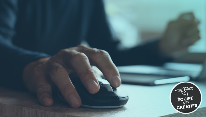 Main d'une personne utilisant une souris d'ordinateur sur un bureau avec un téléphone en arrière-plan.