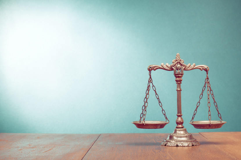 Balance de justice en métal doré sur une surface en bois avec un fond bleu clair.