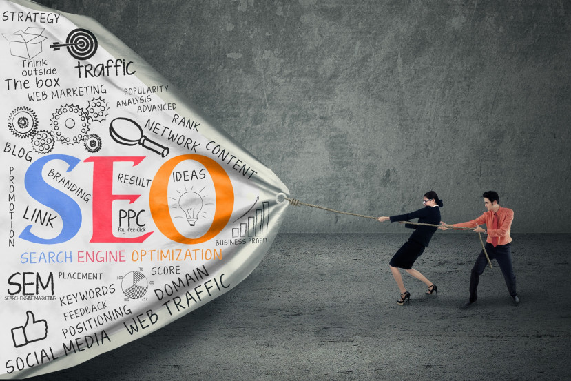 Deux professionnels tirent une grande toile avec des mots liés au SEO et marketing numérique.